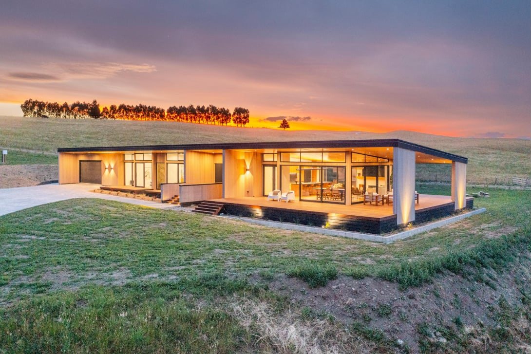 Timber home at Common Ground glowing at sunset among open North Canterbury paddocks
