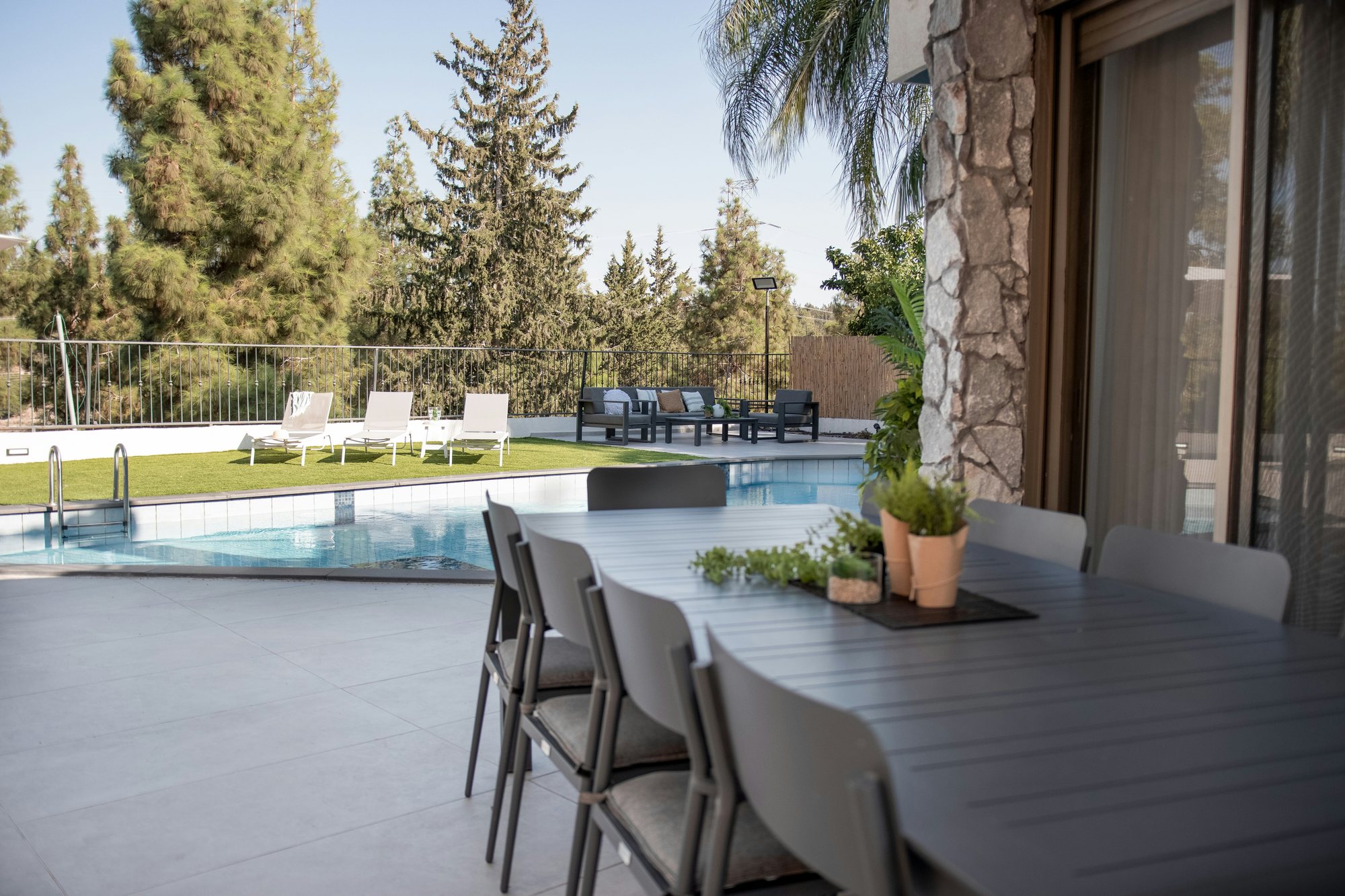 Outdoor dining table on a shared terrace beside the pool at Common Ground